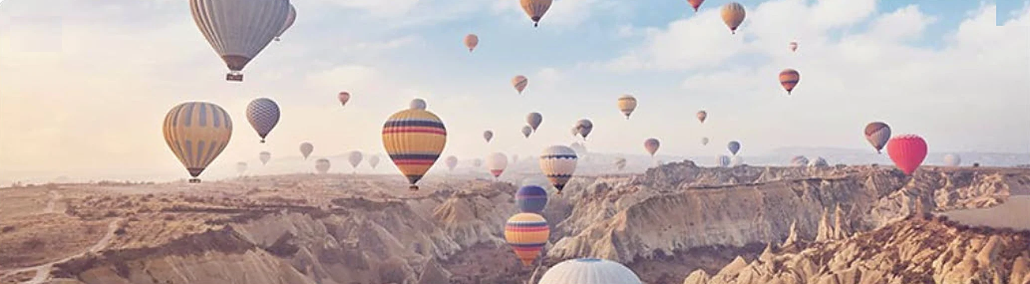 Hot-air balloons over the rock valleys of Cappadocia at sunrise.